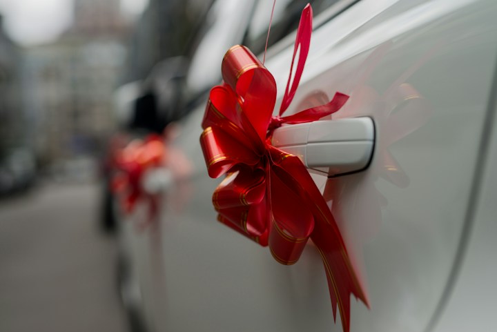 Red bow tied to a white car door handle
