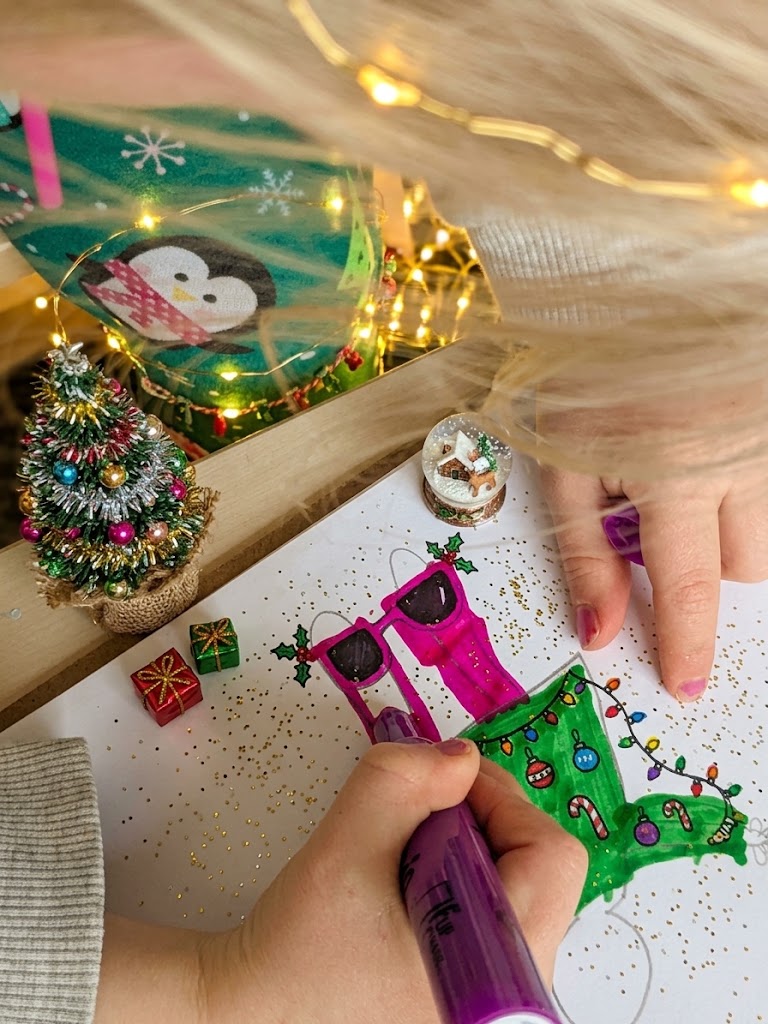 Child coloring a Christmas ornament with markers